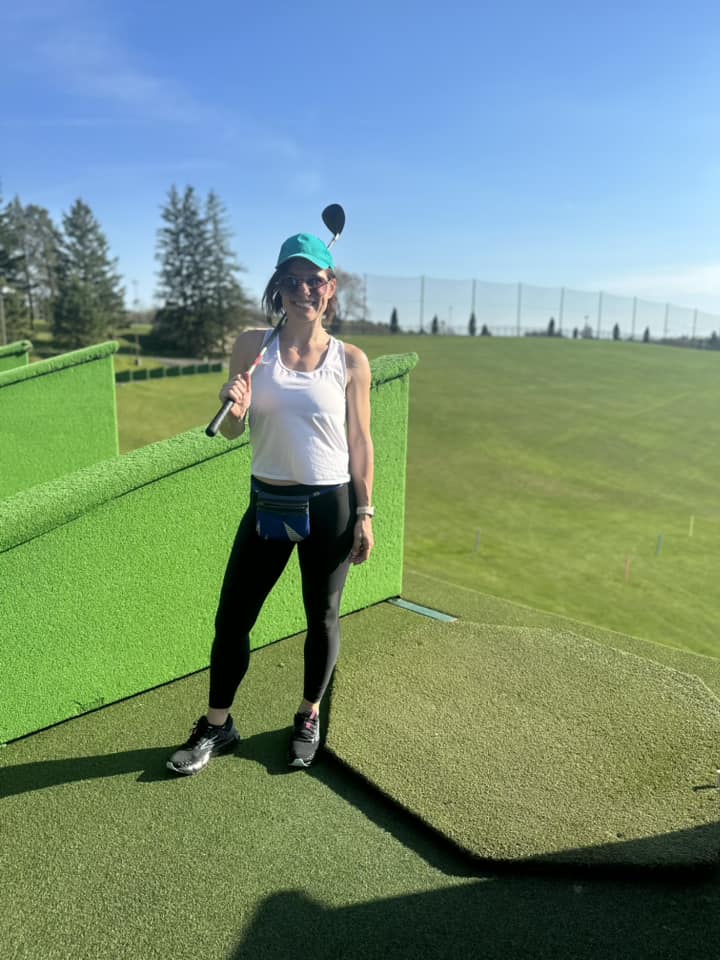 Woman standing at the driving range with golf club over her shoulder