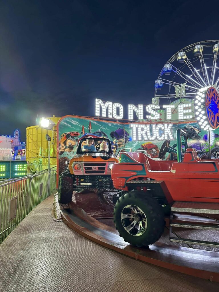 Summer nights at the carnival. Two children riding on a monster truck carnival ride. 